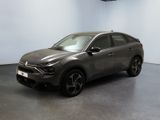Une voiture grise est garée dans une pièce aux murs blancs.