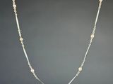 un collier de perles blanches avec une chaîne en or sur fond noir