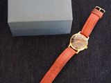 an orange watch sitting on top of a box next to a blue box