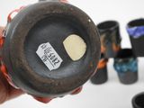 a person holding a black vase with a sticker on it