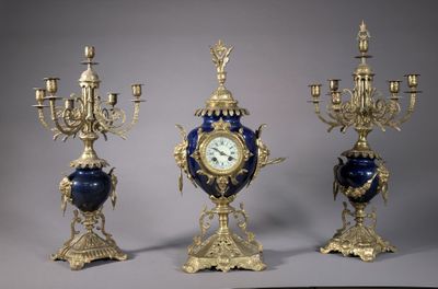 trois vases bleus et dorés, sur chacun desquels se trouve une horloge