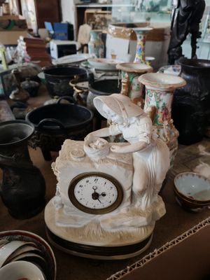 une table sur laquelle se trouvent une horloge, des vases et d'autres objets