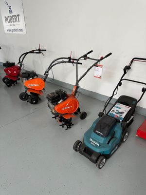 many lawn mowers lined up in a row on the floor