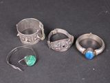 trois bagues en argent et une bague ornée d'une pierre bleue sur un fond noir