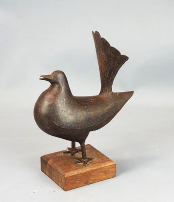 a small bronze bird on a wooden base on a white background