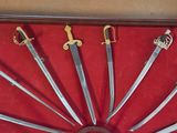 five swords on display in a case on a red surface