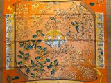 an orange silk scarf with a picture of birds and flowers on it