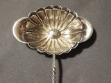 a silver spoon with a flower on it sitting on a table