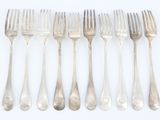 six fourchettes sont alignées en rangée sur une surface blanche