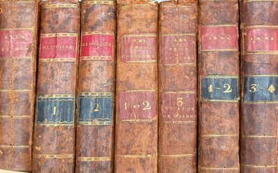 several old books are lined up on a shelf in a library