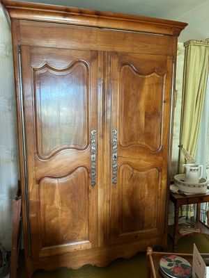 une armoire en bois dans une pièce où se trouvent une table et des chaises
