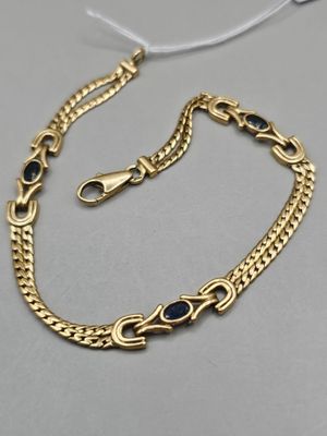 un bracelet en chaîne d'or orné de pierres bleues