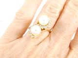 a woman ' s hand holding a pearl and diamond ring