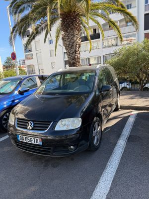 two cars are parked in a parking lot next to a palm tree