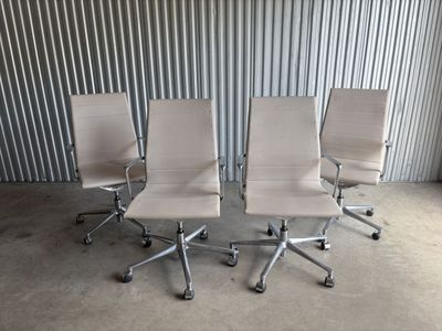 three white office chairs sitting in front of a metal wall