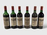 six bouteilles de vin sont alignées sur une surface blanche