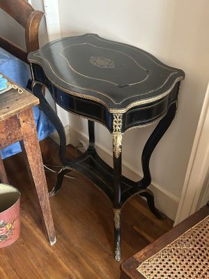 une petite table avec un plateau noir et une chaise à côté