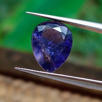 un gros plan d'un saphir bleu tenu par une paire de pinces