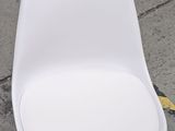 a white chair that is sitting on the sidewalk