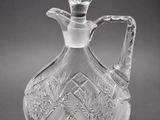 a clear glass decanter with a handle on a black background