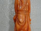 an orange jade figurine of a woman with a hat on