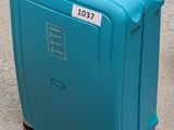 a blue suitcase with a tag on it sitting on the ground