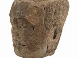 a stone head on a gold stand on a white surface