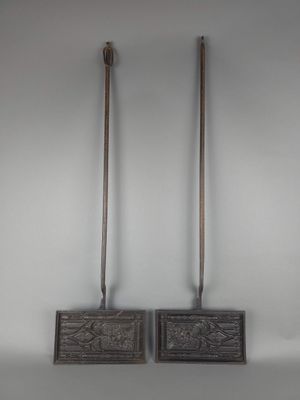 paire d'outils anciens en fonte avec des manches en bois, sur fond blanc