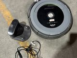 une photo d'un Roombake posé par terre à côté d'un chargeur