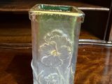 a glass vase with a flower design on it sitting on a table