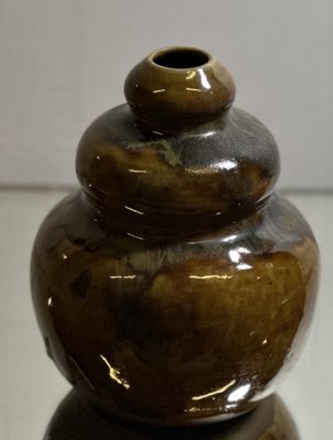 a brown vase sitting on top of a glass table