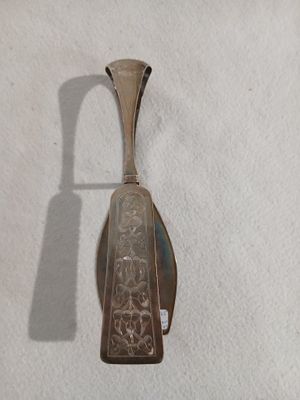 une cuillère en argent avec un manche sur une surface blanche