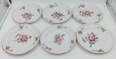 six assiettes ornées de roses, posées sur une table blanche