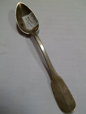 une cuillère en argent, munie d'une étiquette, posée sur une table