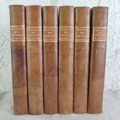 five old books are lined up on a table