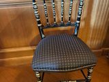 chaise peinte en noir et or dans une pièce aux murs lambrissés