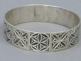 a close up of a silver bracelet with geometric designs on it