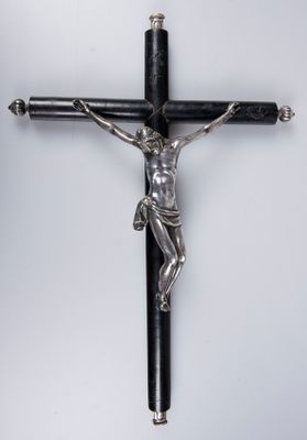 un crucifix en argent sur une croix en bois noir, sur fond blanc