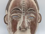 a close up of a wooden mask on a white background