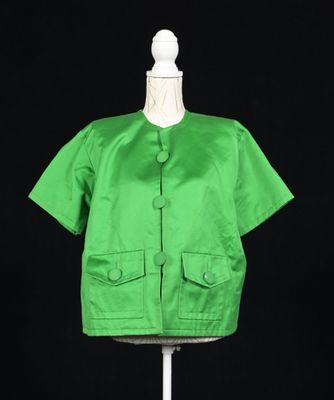 une veste verte posée sur un mannequin, sur fond noir