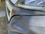 the front end of a car with a dent in it ' s bumper