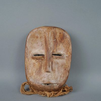 un masque en bois entouré d'une corde, posé sur une surface grise