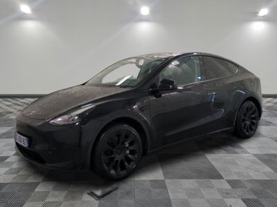 une Tesla Model Y noire garée dans une pièce au sol à carreaux