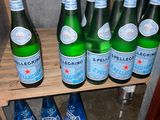 several bottles of water are lined up on a shelf in a cabinet