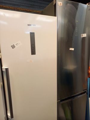 un réfrigérateur argenté et un réfrigérateur blanc dans une pièce