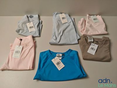Plusieurs chemises sont disposées sur une table, avec leurs étiquettes de prix.