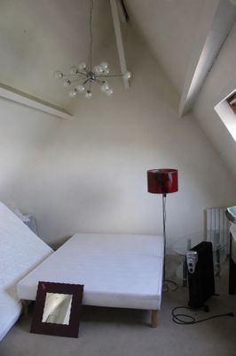 un lit dans un coin d'une pièce où se trouve un miroir accroché au mur