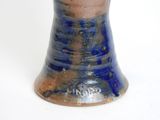 a blue and brown vase sitting on a white surface