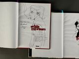 an open book with a drawing of a woman in a dress on it