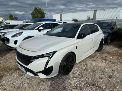 La voiture blanche est garée sur un parking, avec d'autres voitures en arrière-plan.